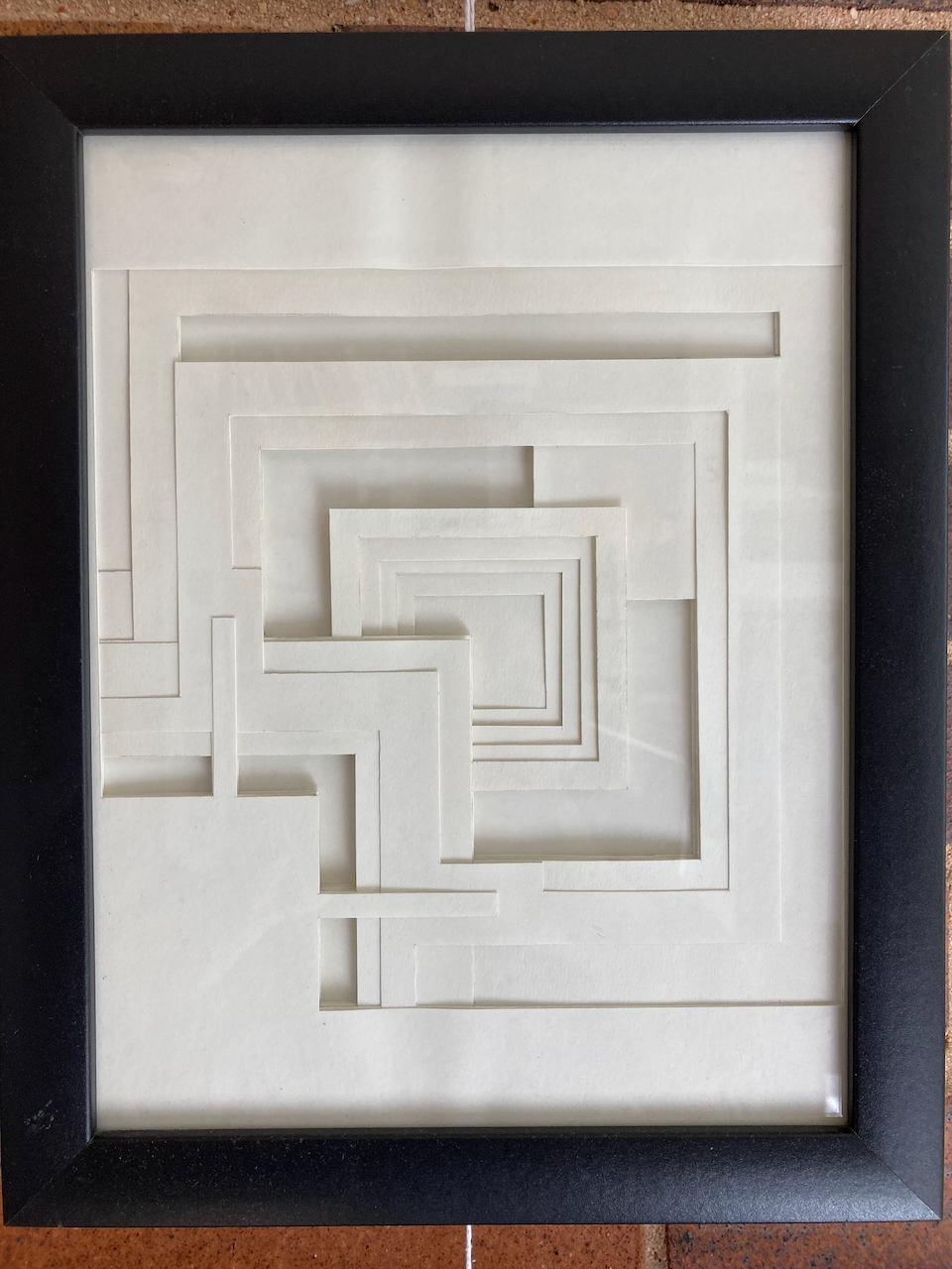 Paper layered Ennis House textile block with brick wall background.